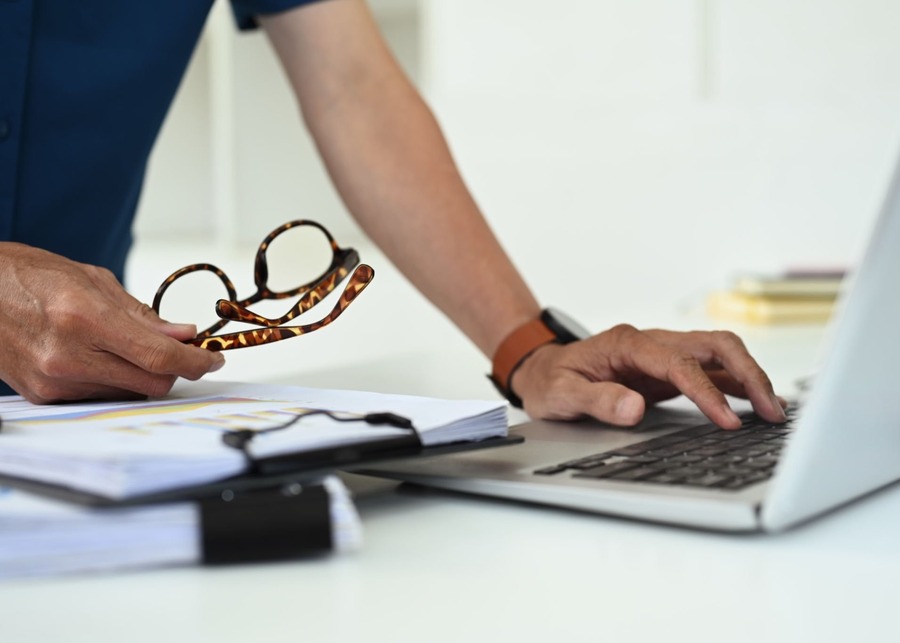 A person using a laptop to research eyewear manufacturers on a professional networking site.